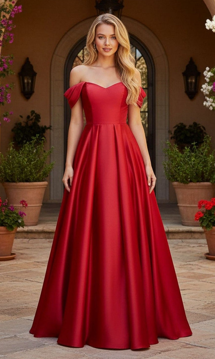 A woman stands outdoors in a stunning red Blondie Nites 6019BN long prom dress with an off-the-shoulder neckline and flowing floor-length skirt, framed by potted plants and an arched doorway in the background.